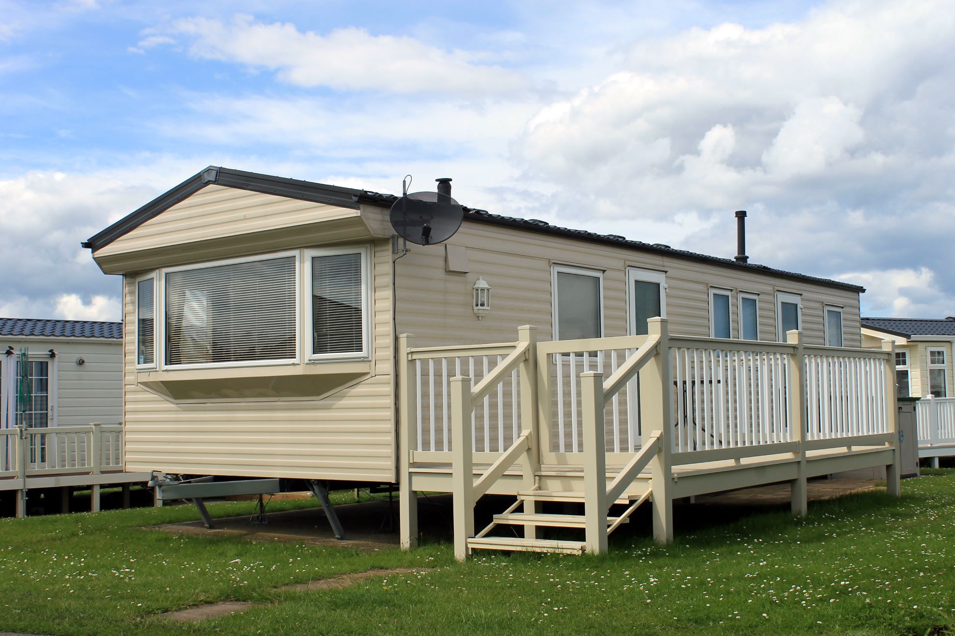 A mobile or manufactured home with a wooden deck.