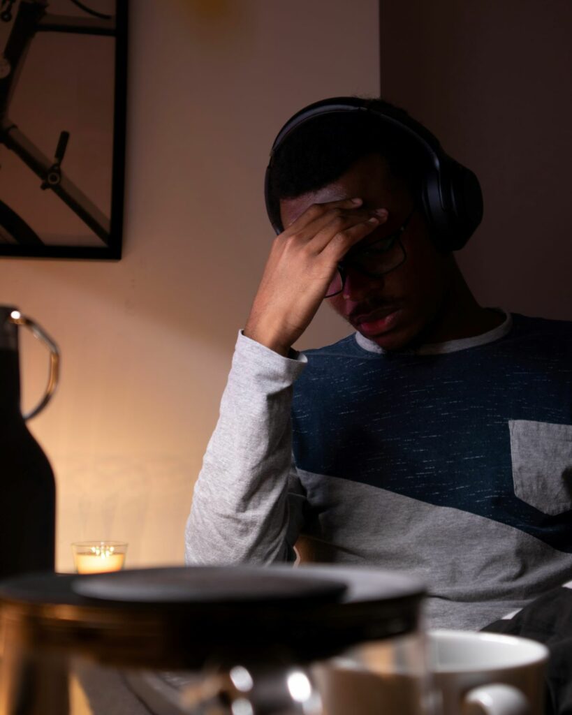 Man wearing headphones and glasses holds his face with his hand, as if experiencing stress or burnout. Wondering how to get into home inspections without burning yourself out? Limit your daily inspections.