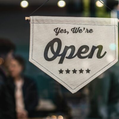 Canvas sign hanging on a business window that reads “Yes, we’re open.” Implies someone is looking for home inspection leads and curious how to get work as a home inspector.