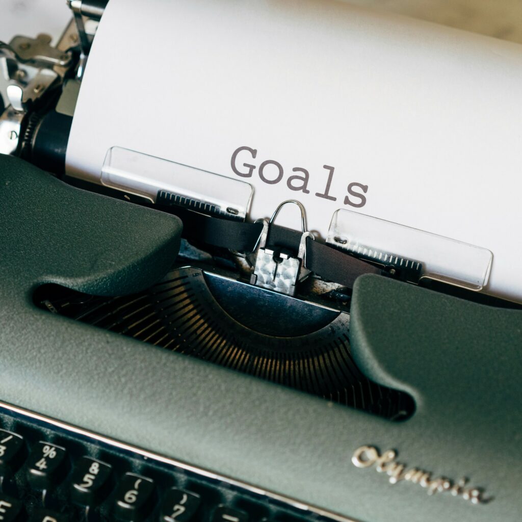 Green Olympia typewriter with "Goals" written on the emerging paper. The key to home inspection lead generation is to set measurable goals.