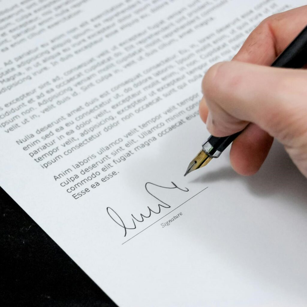 Close-up of a hand holding a pen and signing a contract before a home inspection.