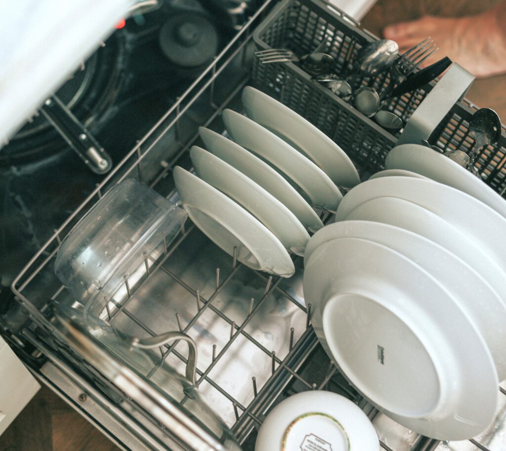 Open dishwasher drawer loaded with plates and silverware.