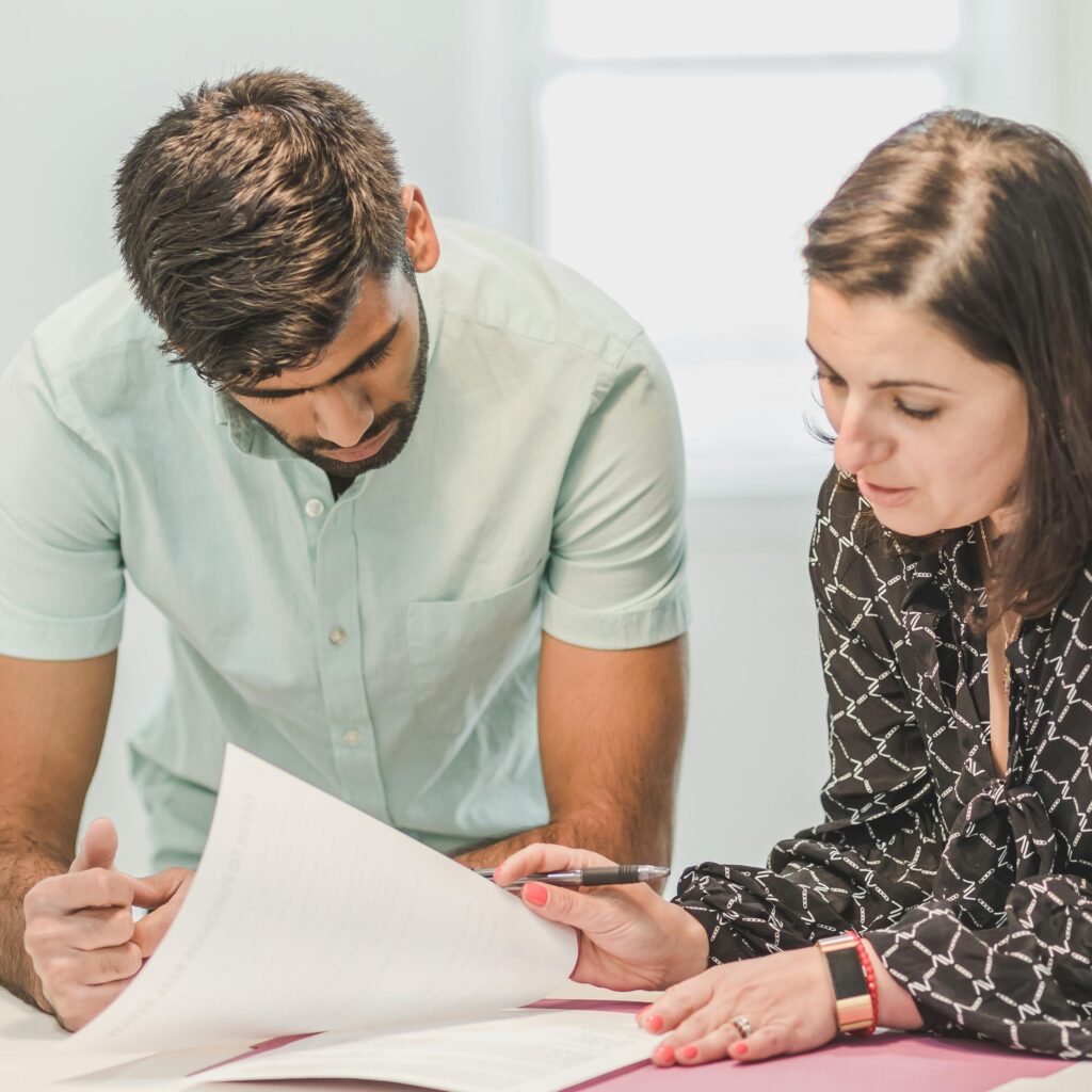 Woman reads through paperwork with a man, presumably like home inspectors and real estate agents.