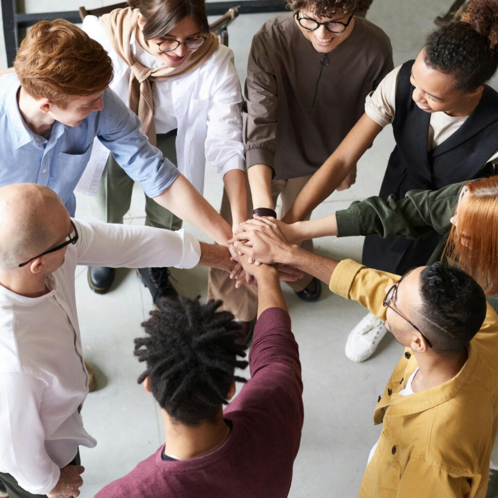 A group of people stand in a circle with one hand in the middle, as if inspecting an estate as a team.