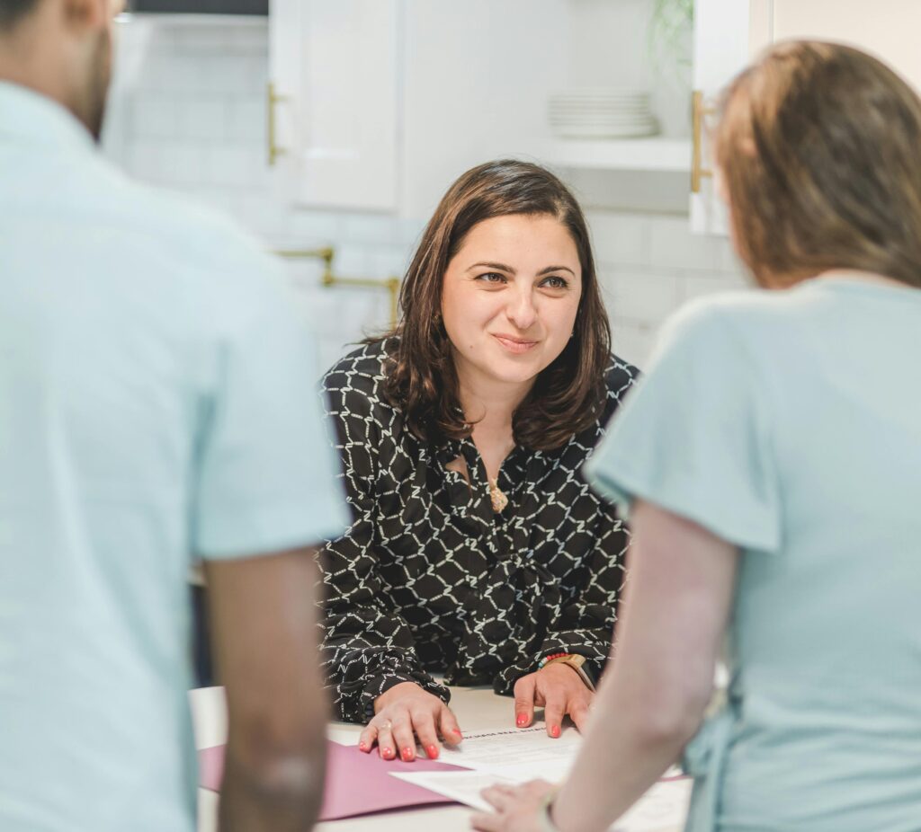 A woman smiles at two people who are facing away from the camera.